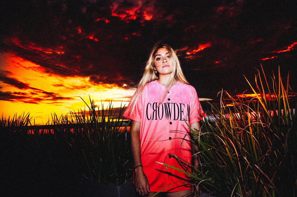 Blonde female artist wearing Mars Jersey, out in a field as the sun sets. 