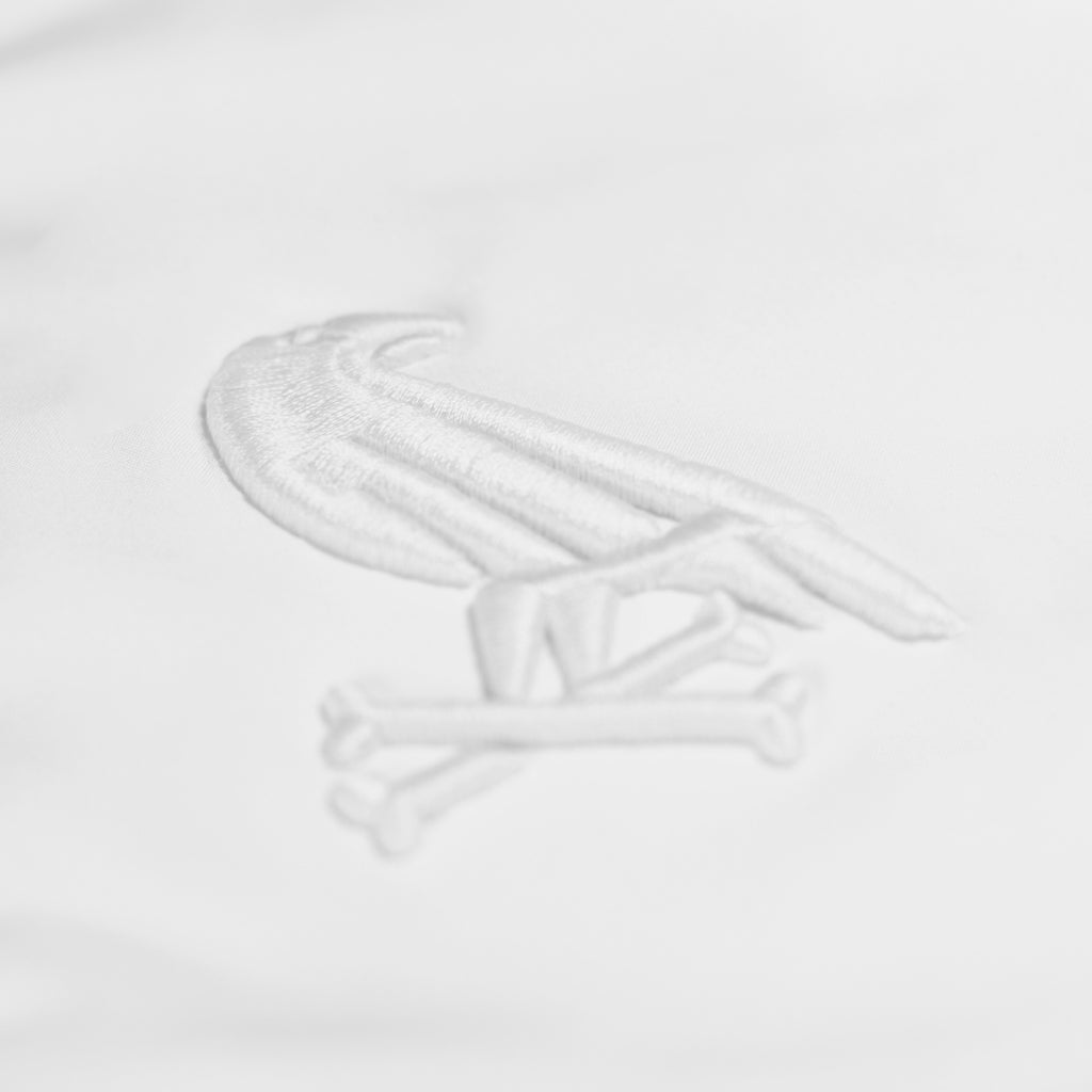 White jacket by Crowdead. Front Crow & Crossbones embroidered logo closeup.